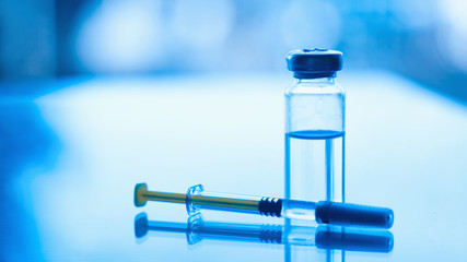 Vials of medication and syringe on a blue glass table with window background. Insulin syringe and diabetes needle. diabetic supplies background