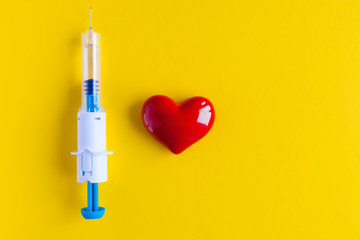 Volumetric heart shape with a syringe on a yellow background. Congenital heart defect