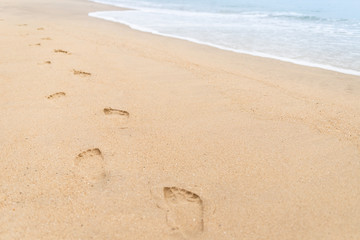 Fototapeta na wymiar Footprints walking on the beach and waves