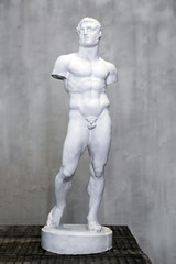 Statue of naked young man, armless, Roman and Greek art. Small plaster copy of sculpture.