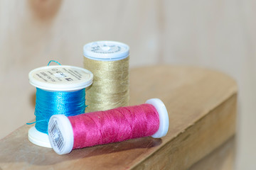 pink blue and beige threads on a wooden table