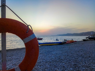 Orange emergency lifebuoy on a pebbly sea beach, close up