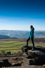 Naklejka premium Woman stands on cliff edge viewing rolling English hills on a sunny day