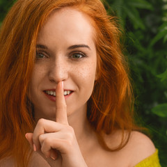 Naklejka premium Young redhead girl asking to keep silence