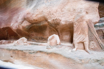 Antique man and camel sculptures carved in sandstone wall of Siq passage in Petra, Jordan.