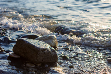 rocky sea shore with pebble beach, waves with foam