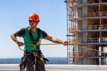 High rise rope technician window cleaner is working on a construction site during a sunny summer...