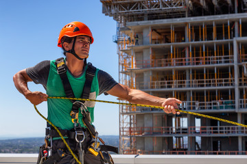 High rise rope technician window cleaner is working on a construction site during a sunny summer day. Taken in Burnaby, Vancouver, BC, Canada.