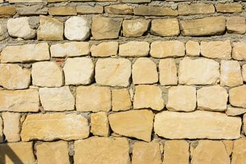 beautiful background. yellow natural stone wall in sunlight
