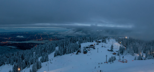 Panoramic view of Grouse Mountain Ski Resort during a cloudy winter sunset. Taken in North Vancouver, British Columbia, Canada.