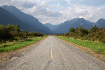 Scenic road surrounded by Canadian Mountain Landscape during a vibrant summer day. Taken in Pitt Meadow, Greater Vancouver, BC, Canada.