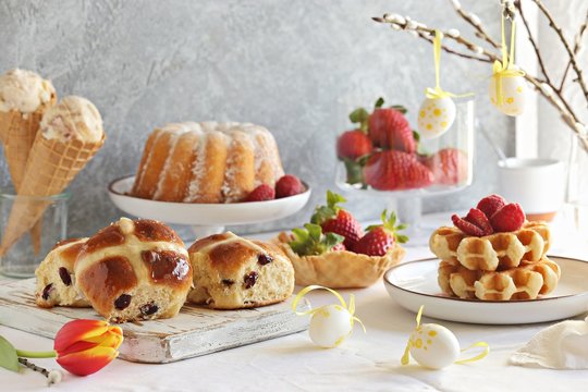 Easter festive dessert table with hot cross buns, cakes and waffles. 