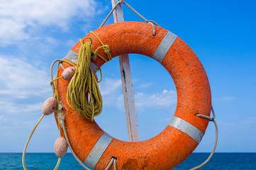 Orange emergency lifebuoy on a pebbly sea beach, close up