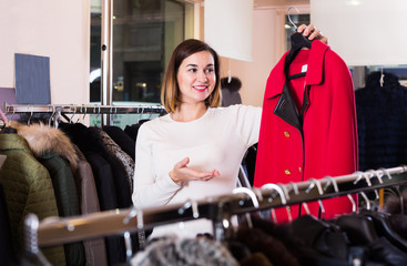 Nice female customer examining red woolen coat