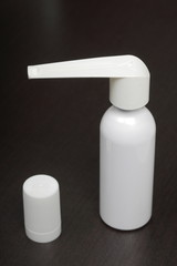 Inhaler for the treatment of respiratory organs. Spray can and cap white. On a dark surface.