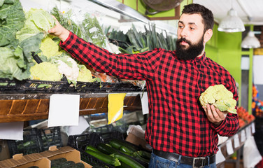 Man seller holding cauliflowers in vegetables shop