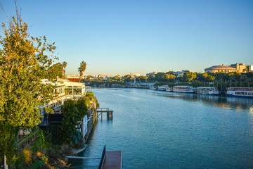 The Guadalquivir river that flows through Seville in the south Spain with riverboats lining the riverfront in the early morning.