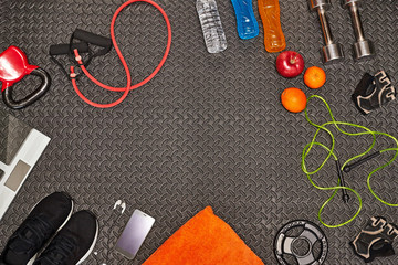 Fitness concept.Fruits, gym equipment,water, energy drinks and sport clothing on gray background.Healthy lifeslile.