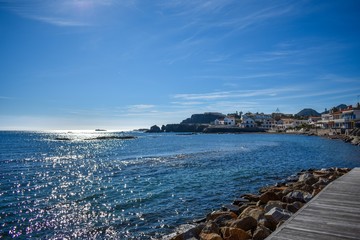 Blue skies and bluer water frame houses on the rocky beachfront of Cabo de Palos, Spain