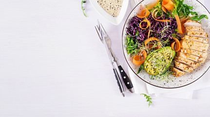 Buddha bowl dish with chicken fillet, avocado, red cabbage, carrot, fresh lettuce salad and sesame. Detox and healthy keto diet bowl concept. Overhead, top view, flat lay, copy space