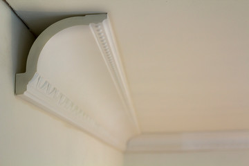 Close-up detail of decoration white molding connected with glue adhesive to wall and ceiling in interior room renovation and reconstruction.