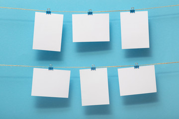 place for photo cards of moments of life, empty blanks attached to a linen rope with stationery clips on blue background, a concept template for text, images, idea for home decor