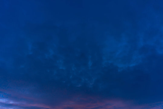 Amazing dramatic blue cloudy sky nightly. Atmospheric minimalist natural background of night in overcast weather. Hard cloudiness. Storm clouds warning. Beautiful dark cloudscape. Darkness. Copy space