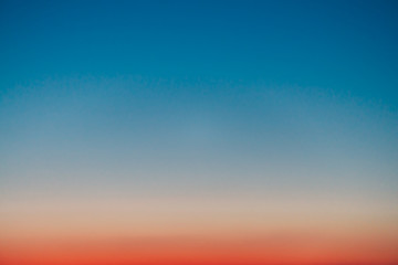 Predawn clear sky with red horizon and blue atmosphere. Smooth orange blue gradient of dawn sky. Background of beginning of day. Heaven at early morning with copy space. Sunset, sunrise backdrop.