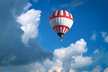 A beautiful big balloon in a bright blue sky between white clouds