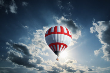 Large red-white balloon on a sunny day between clouds