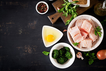 Ingredients for homemade Fish Cake cod, spinach, egg and breadcrumbs. Raw cutlets from minced cod. Top view.