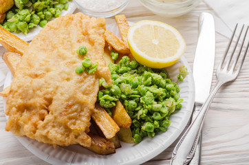 Traditional British street food fish and chips with tartar sauce and mushy peas on paper plate