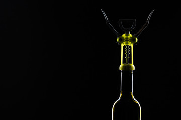 Bottle of wine with corkscrew on the black stone background