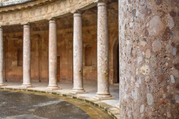 A close-up of a palace pillar showing its texture with identical pillars in the background surrounding a circular plaza in Granada, Spain 