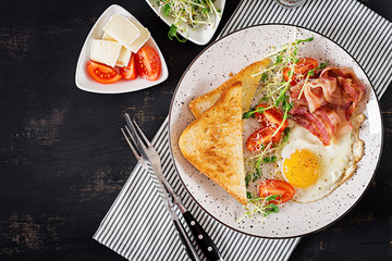 English breakfast - toast, egg, bacon and tomatoes and microgreens salad. Top view. Flat lay