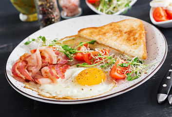 English breakfast - toast, egg, bacon and tomatoes and microgreens salad.