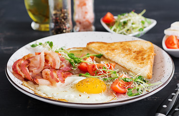 English breakfast - toast, egg, bacon and tomatoes and microgreens salad.