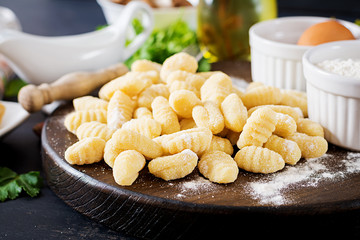 Uncooked homemade Gnocchi with a mushroom cream sauce and parsley  in bowl on a dark background.