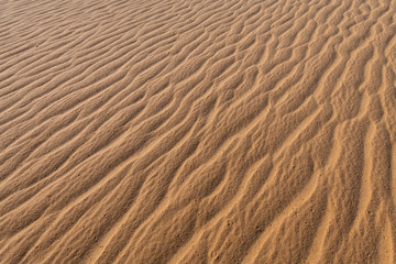 Amazing abstract background image of ripples and waves in the sand at sunrise