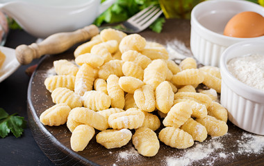 Uncooked homemade Gnocchi with a mushroom cream sauce and parsley  in bowl on a dark background.