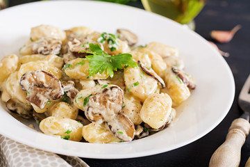 Gnocchi with a mushroom cream sauce and parsley  in bowl on a dark background
