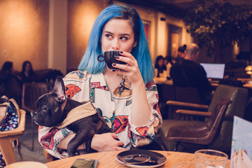 Young hipster woman in cafe with dog drinking coffee 