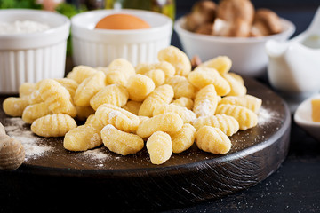 Uncooked homemade Gnocchi with a mushroom cream sauce and parsley  in bowl on a dark background.