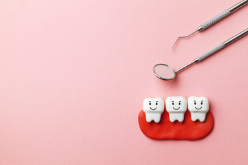 Healthy white teeth are smiling on pink background and dentist tools mirror, hook. Copy space for...