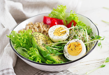 Fresh salad. Breakfast bowl with oatmeal, paprika, avocado, lettuce, microgreens and boiled egg. Healthy food. Vegetarian buddha bowl.