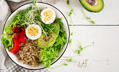 Fresh salad. Breakfast bowl with oatmeal, paprika, avocado, lettuce, microgreens and boiled egg. Healthy food. Vegetarian buddha bowl. Top view