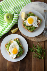 Sandwich or bread toast with avocado and a fried egg on a white plate on rustic wood table. Healthy food. Healthy eating.