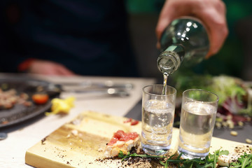 Person filling glasses with vodka