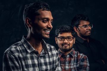 Three black-skinned friend smiling and posing on camera in the studio on a black background