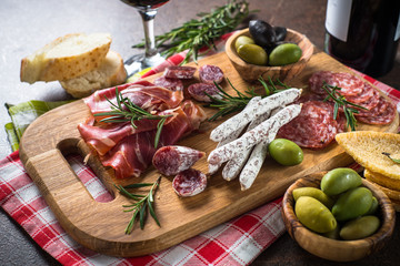 Antipasto delicatessen - sliced meat, ham, salami, olives on wooden board. 
